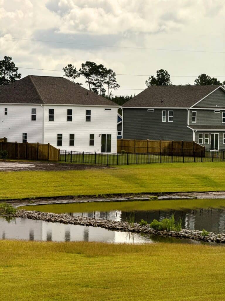 Newly built houses with fenced yards near a pond in Pender County.