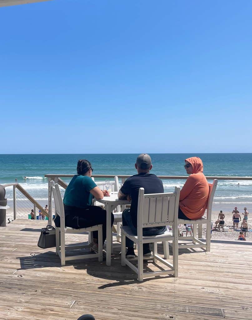 People sitting at a restaurant table overlooking Surf City Beach in North Carolina.