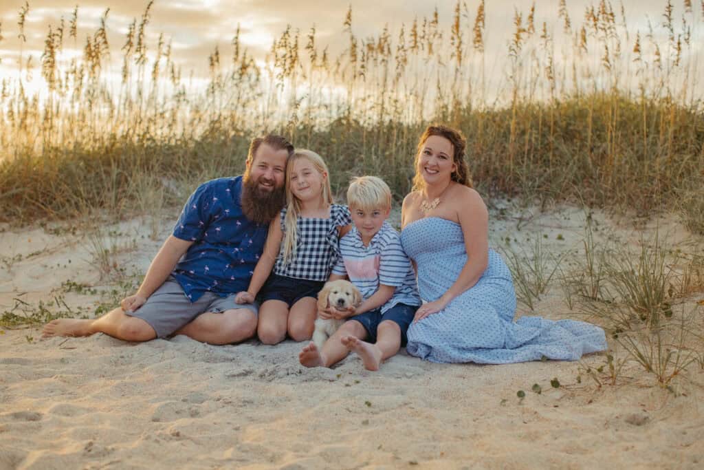 Happy family sitting on the beach at sunset in Wilmington, NC.
