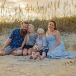 Happy family sitting on the beach at sunset in Wilmington, NC.