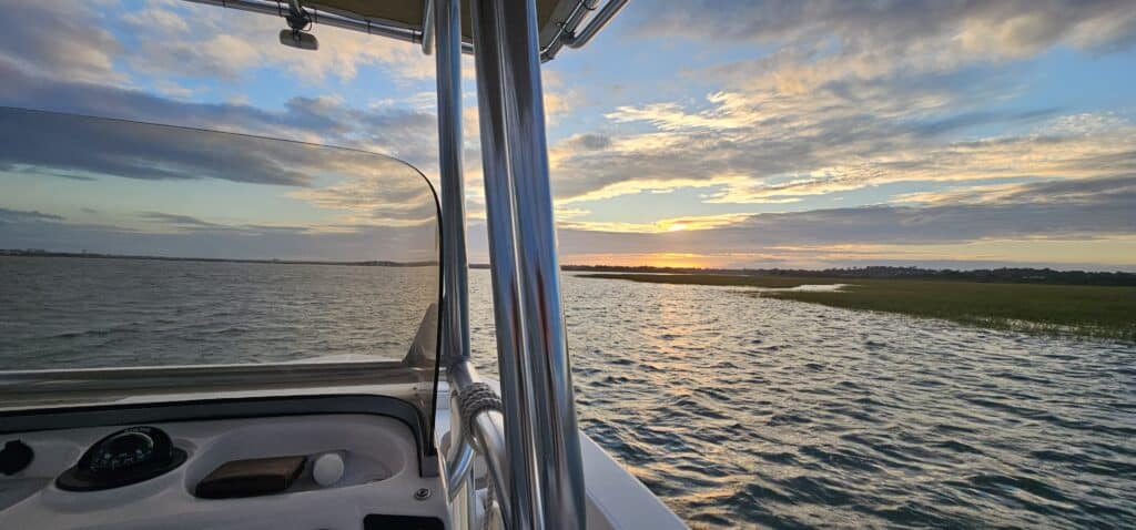 Beautiful sunset over water seen from a boat with a clear sky and calm waves.
