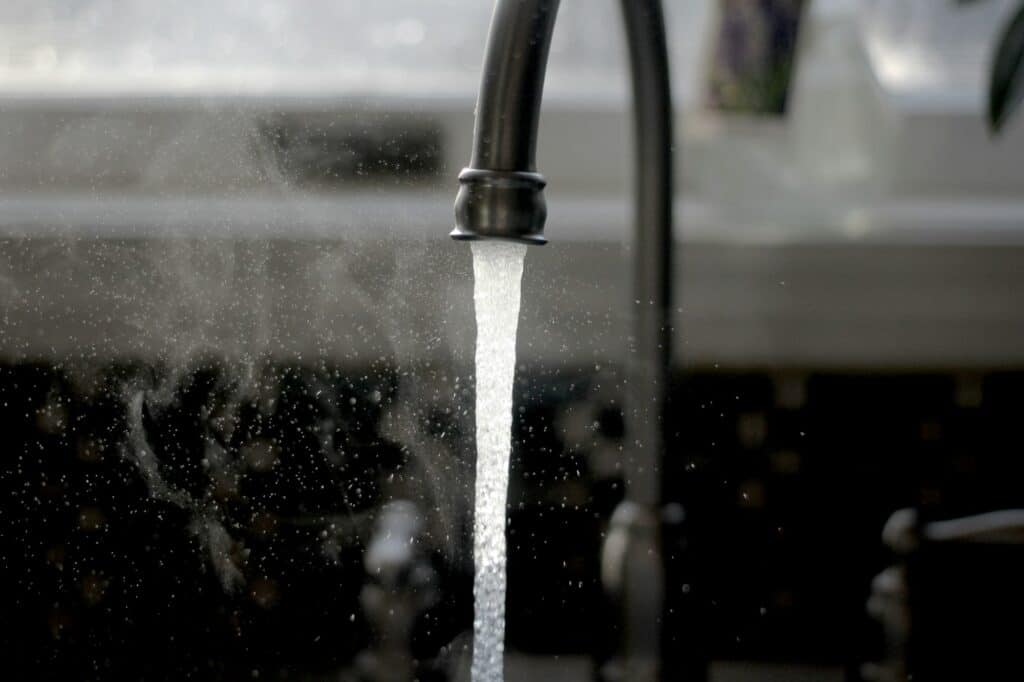 Close-up of a kitchen faucet running clear tap water into a sink