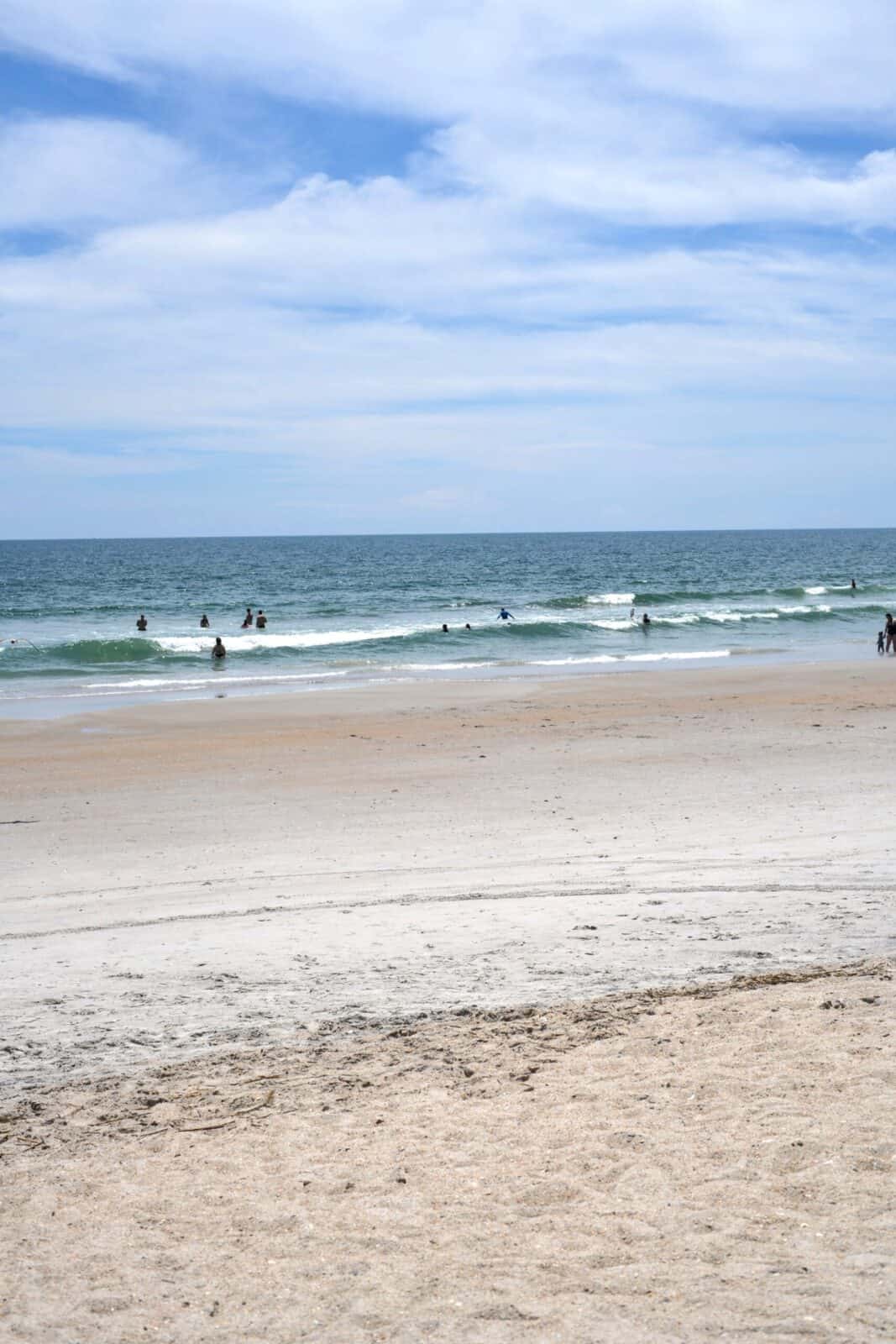 Gentle waves and swimmers along the sandy Atlantic shoreline at Wrightsville Beach, NC.