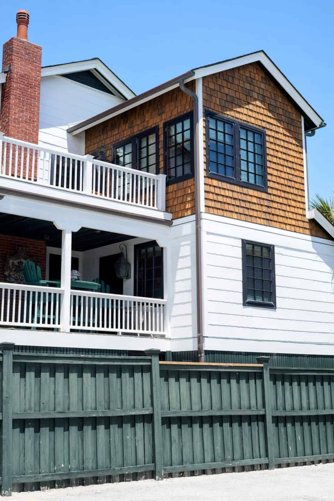 Classic shingle-and-cedar beach house with double porches behind a green fence in Wrightsville Beach, NC.