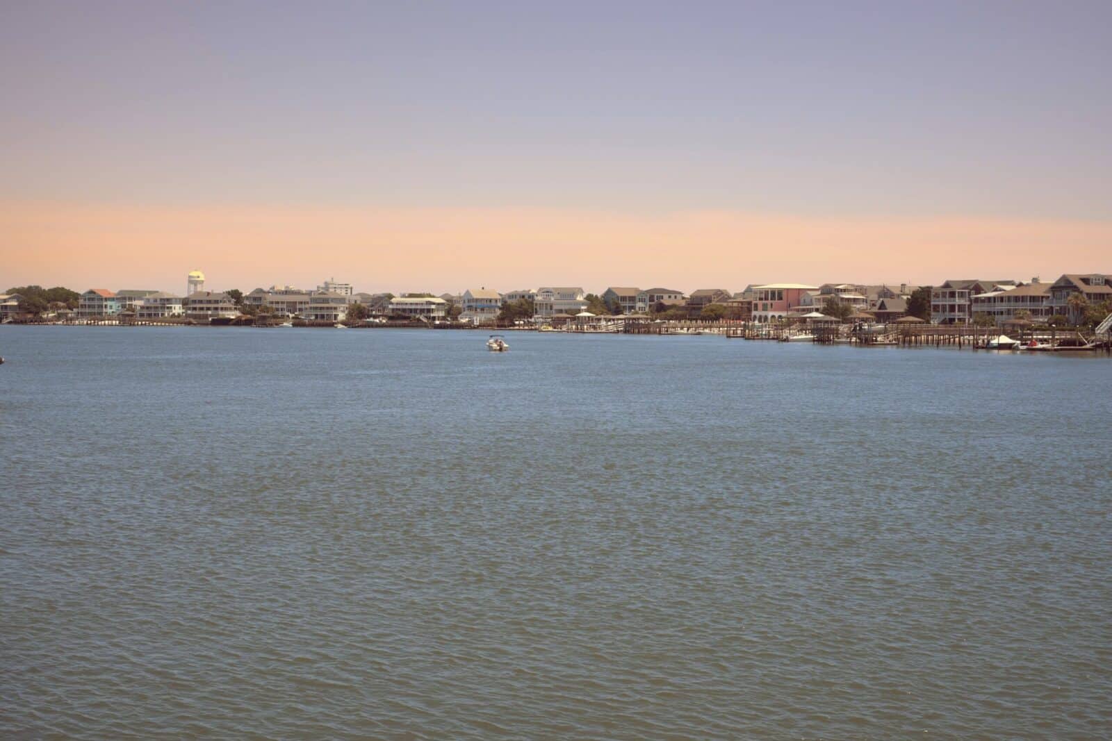 Scenic waterfront view of houses and buildings at sunset.