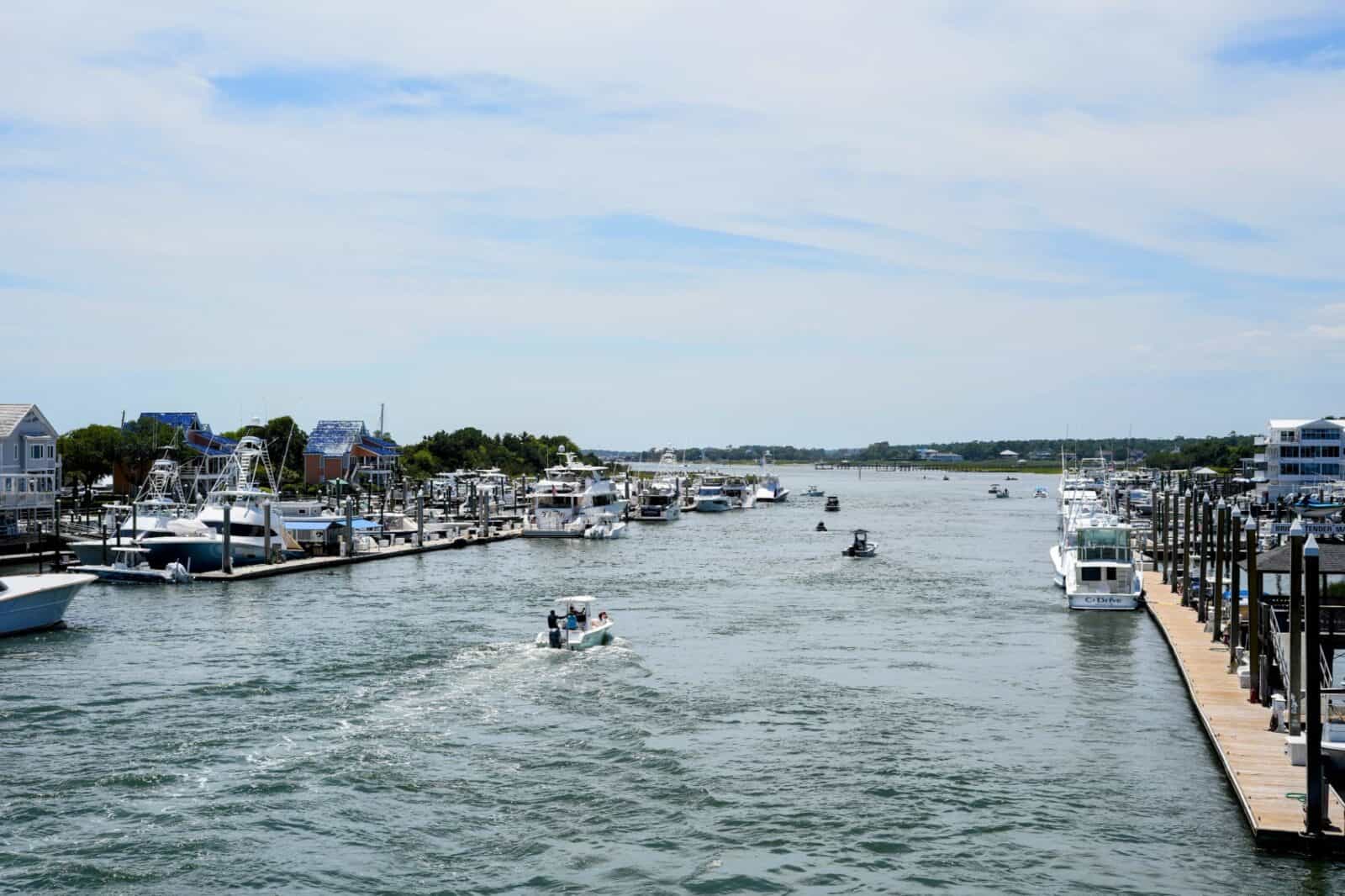 Boats cruising the Intracoastal Waterway past marinas and waterfront homes in Wrightsville Beach, NC.