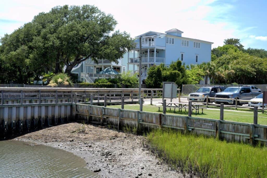 Coastal home with water view, trees, and parking area in ILM.