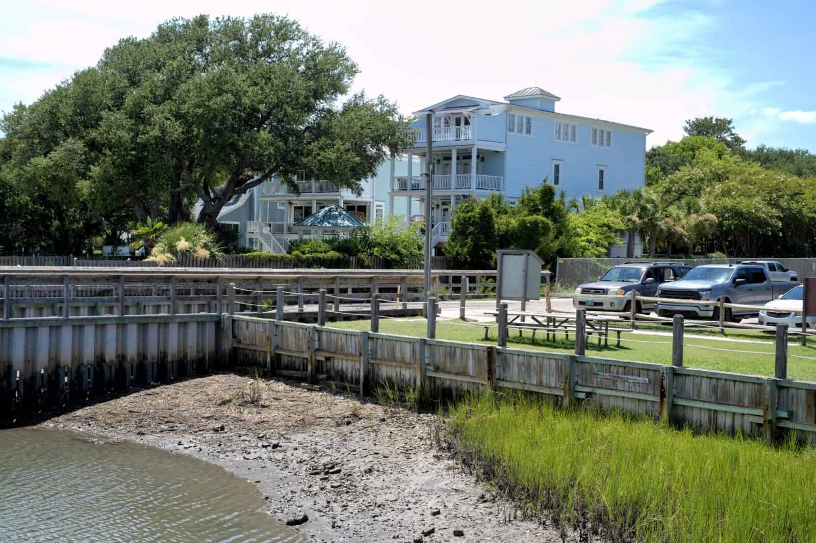 Waterfront homes and a boardwalk overlooking a marsh cove at low tide in Wrightsville Beach, NC.