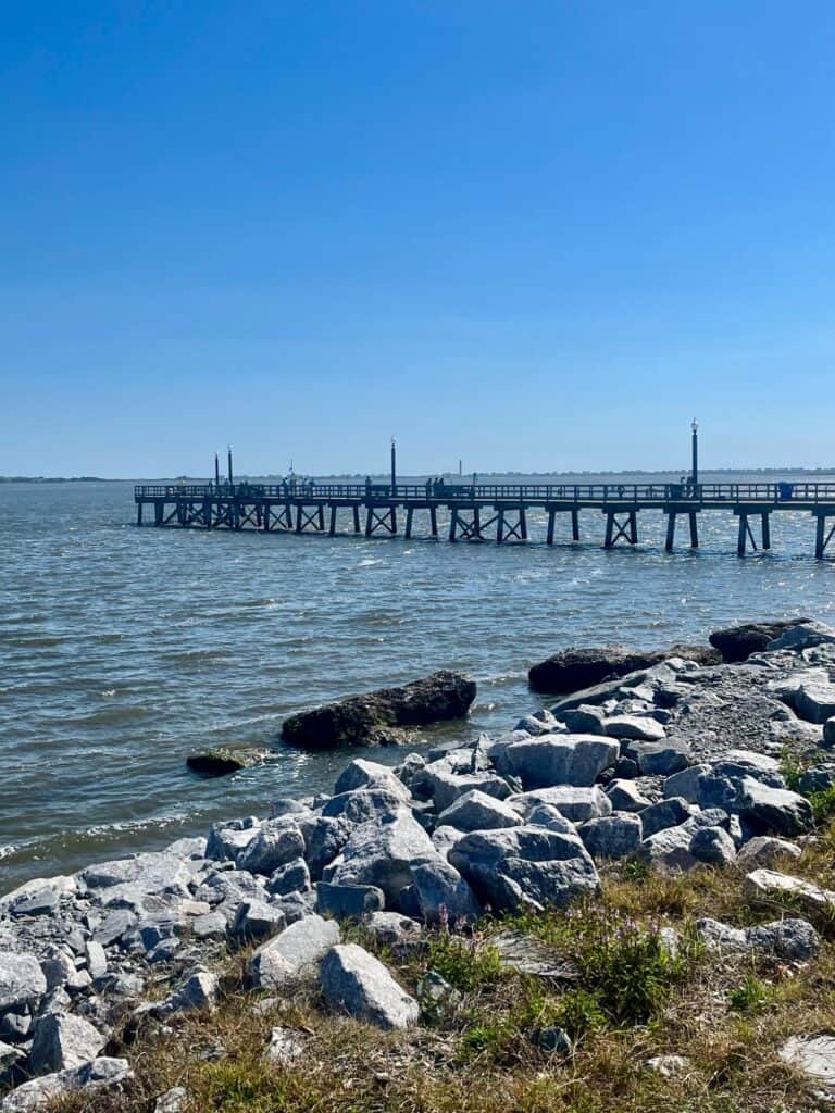 Wooden fishing pier over calm water at one of the Brunswick County beaches near Southport, NC.