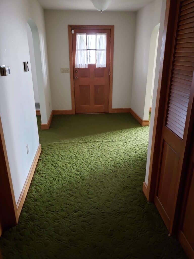 Entry hallway with green carpet before renovation
