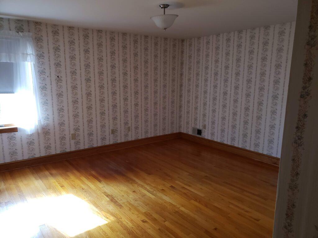 Primary bedroom before renovation with striped floral wallpaper
