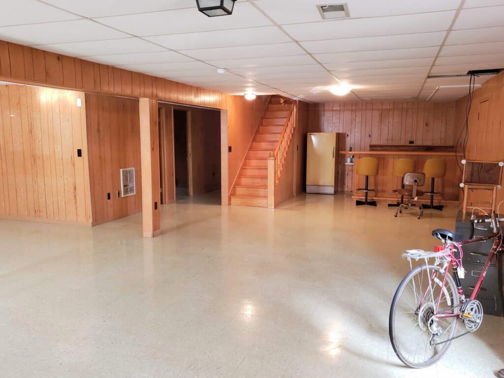 Basement rec room before renovation with knotty pine paneling