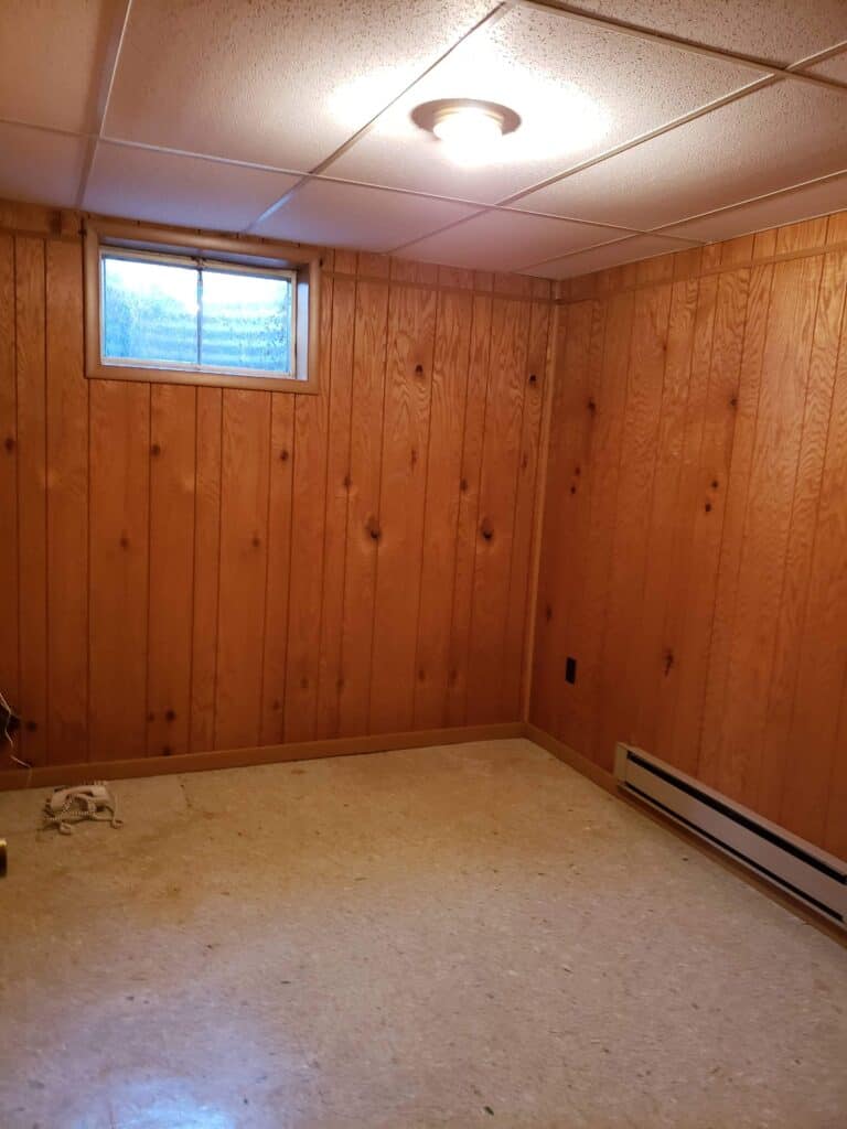 Basement bedroom before renovation with wood paneling