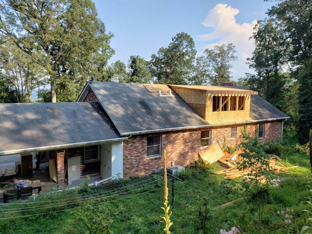 Roof torn off the 1970s rancher with new dormers being framed