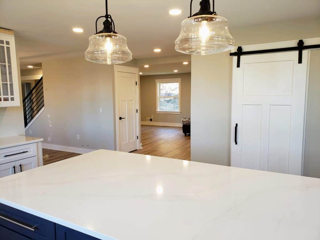 Renovated kitchen island with glass pendant lights and barn door