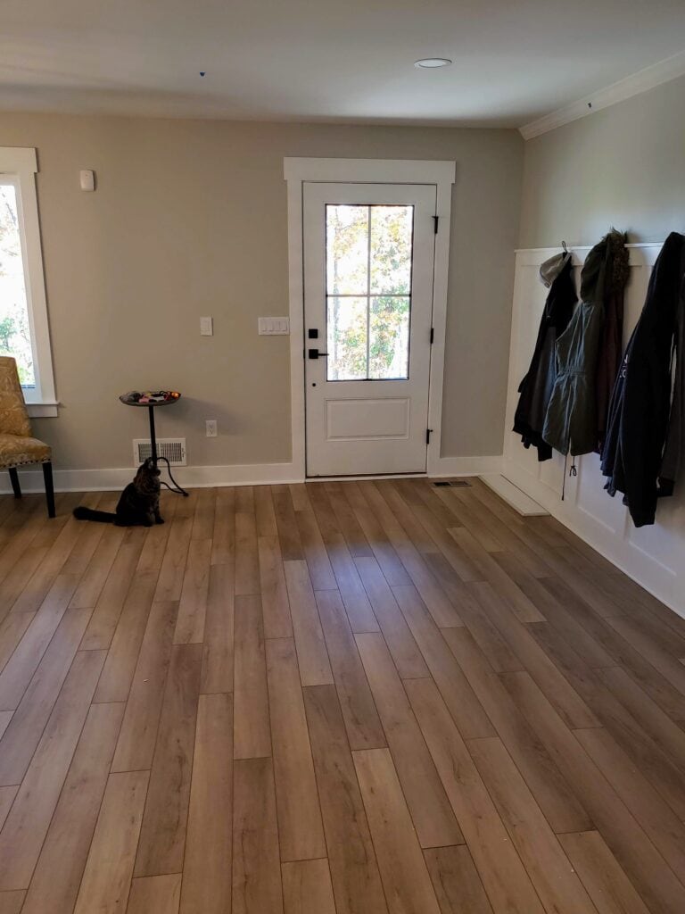 Renovated entry with wood-look floors and white front door