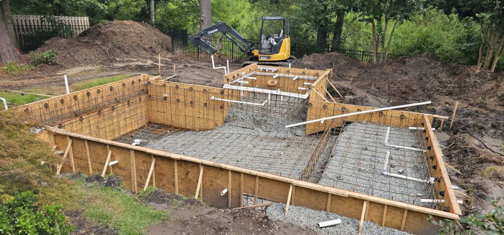 Wooden forms and rebar set up for the pool and spa while the excavator finishes grading