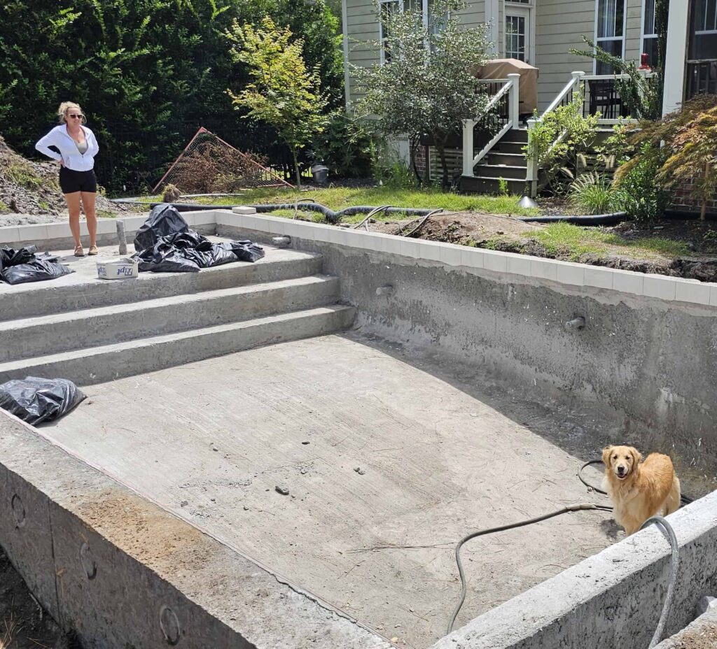 Golden retriever puppy sitting in the deep end of the empty pool shell