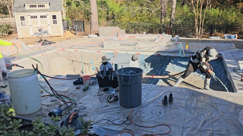 Crew applying the pebble interior finish inside the pool