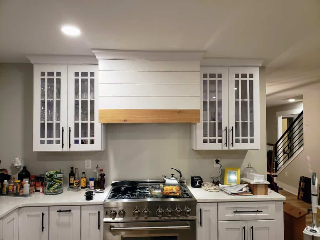 New range wall with white cabinets and shiplap hood