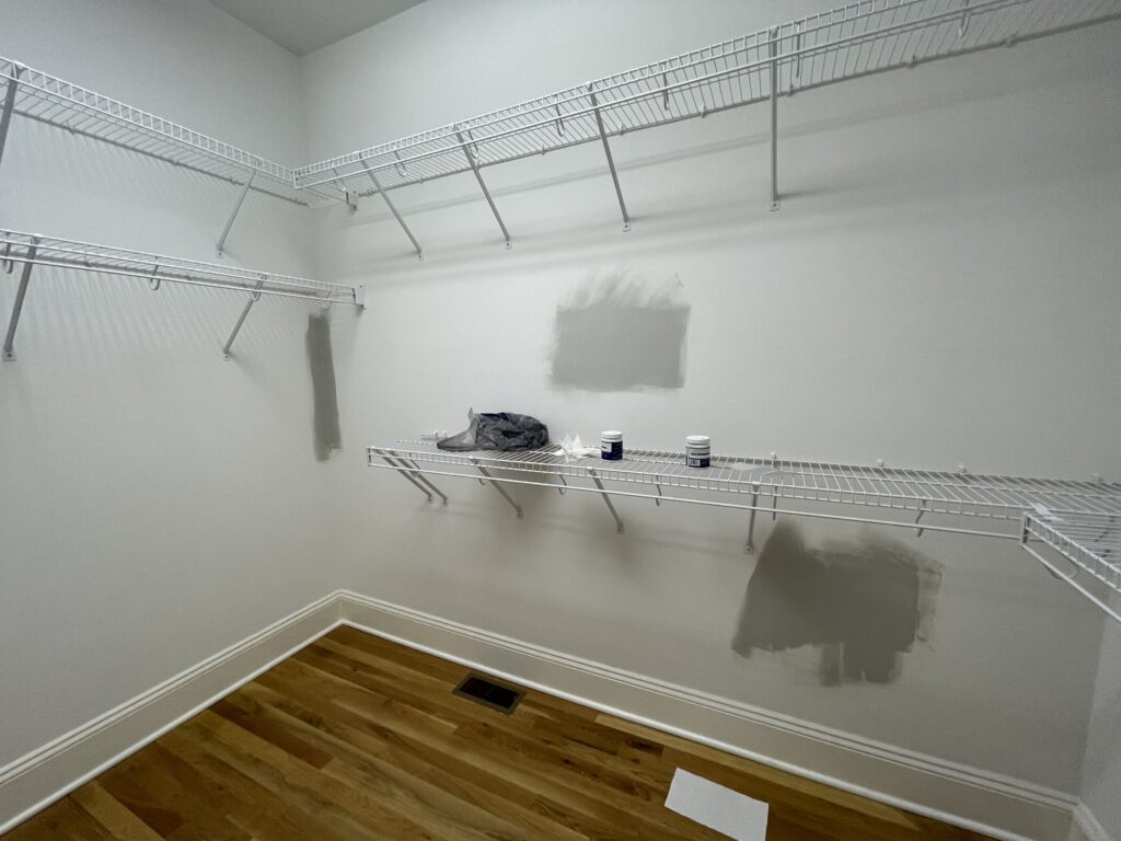 Walk-in closet before the makeover with wire shelving and patched drywall