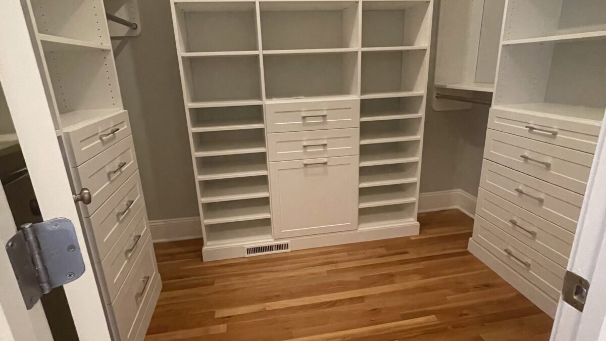 Finished walk-in closet with a white custom closet system, drawers, shelves and double hanging rods