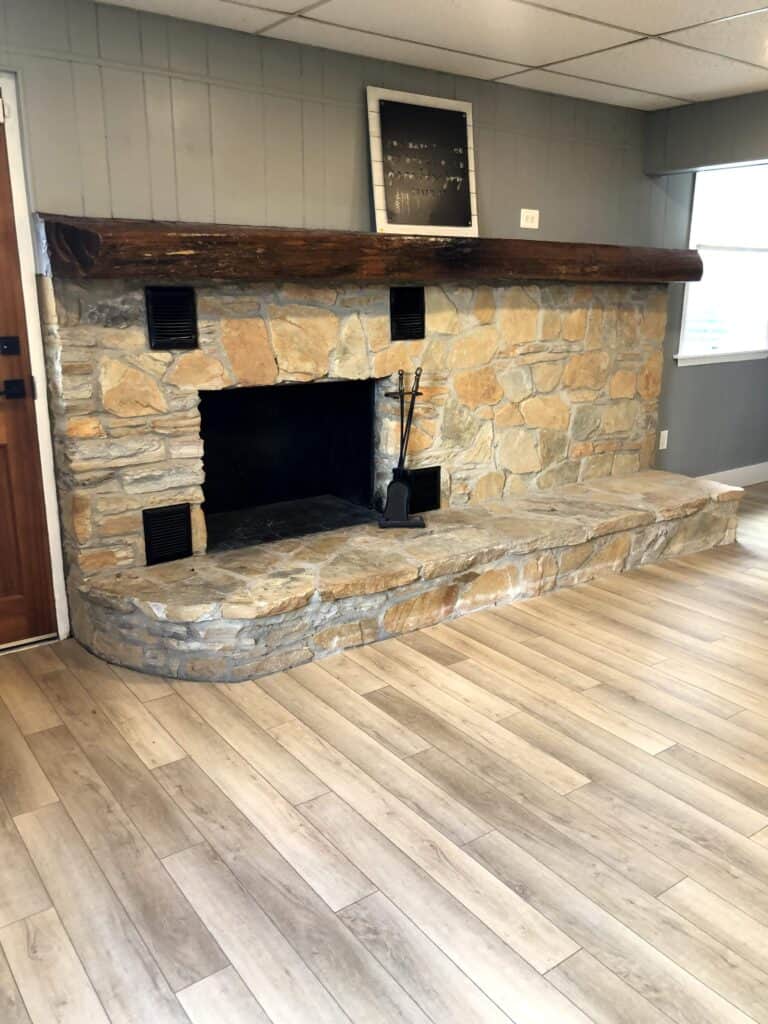 Basement stone fireplace after renovation with new floors