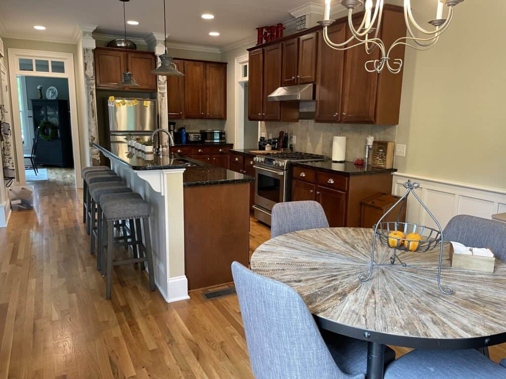 Kitchen before the remodel with dark wood cabinets, dark granite countertops and a raised bar island