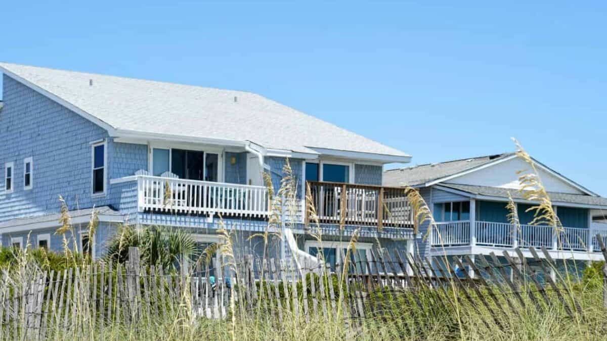Coastal beach house with blue siding and white railings on elevated decks.