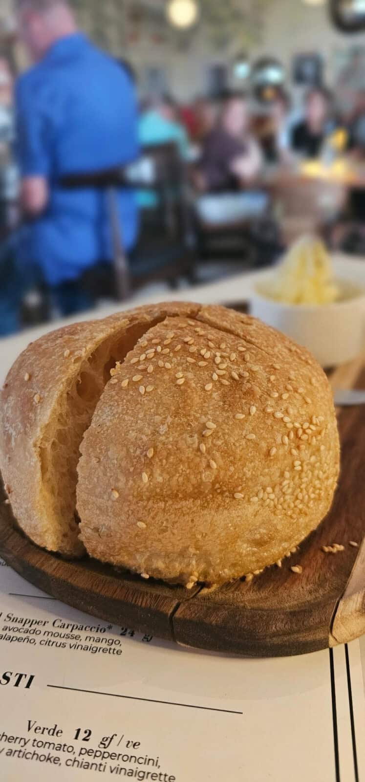 Fresh-baked sesame-topped bread on a wooden board at Fortuna Cucina Italiana in Wilmington NC