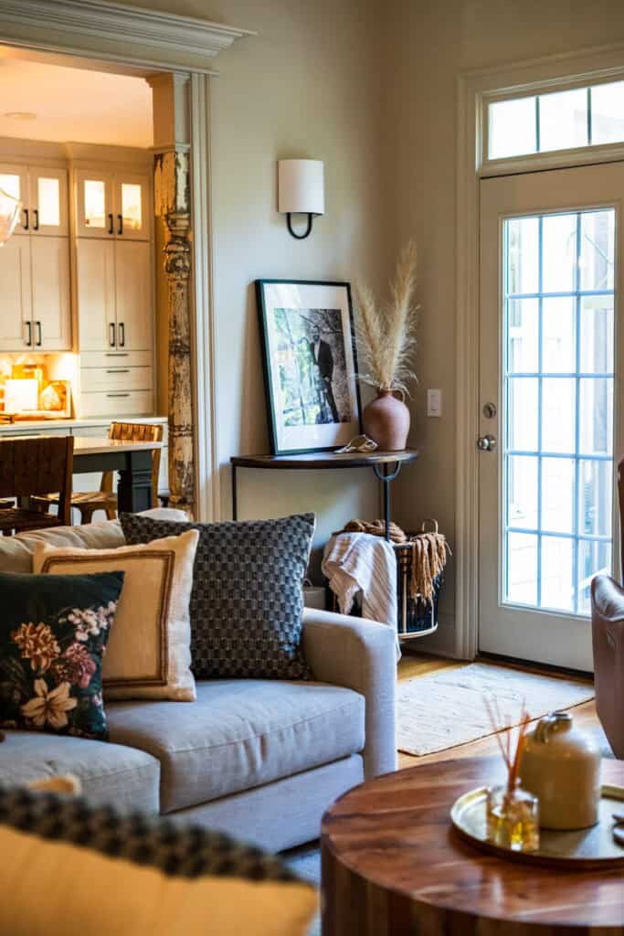 Bright living room with sofa, pillows, and a glass door leading outside.